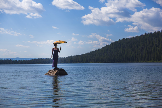 Woman With Umbrella on Rock in Lake
