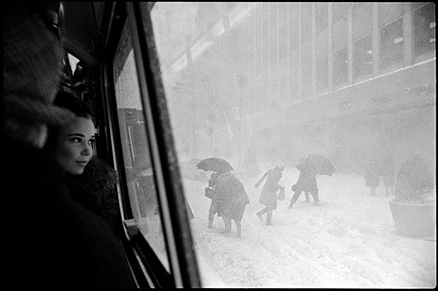 USA. New York City. 1967. Girl in bus and figures in street during snowstorm.