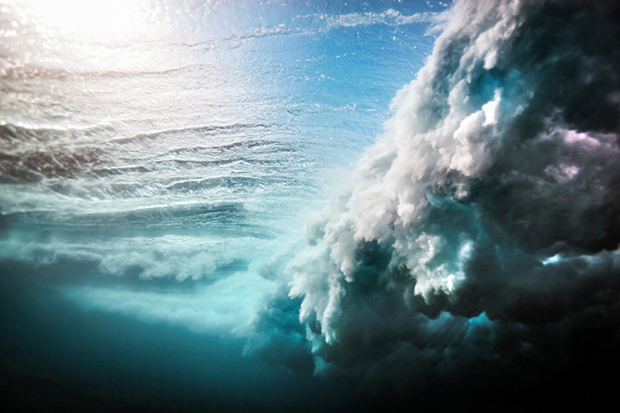 Low angle underwater view of huge wave crashing over a shallow reef