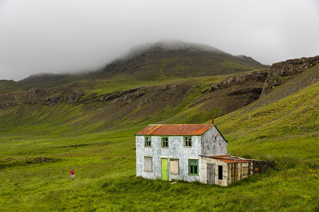 Distant view of girl playing near abandoned house, Stryta, Iceland